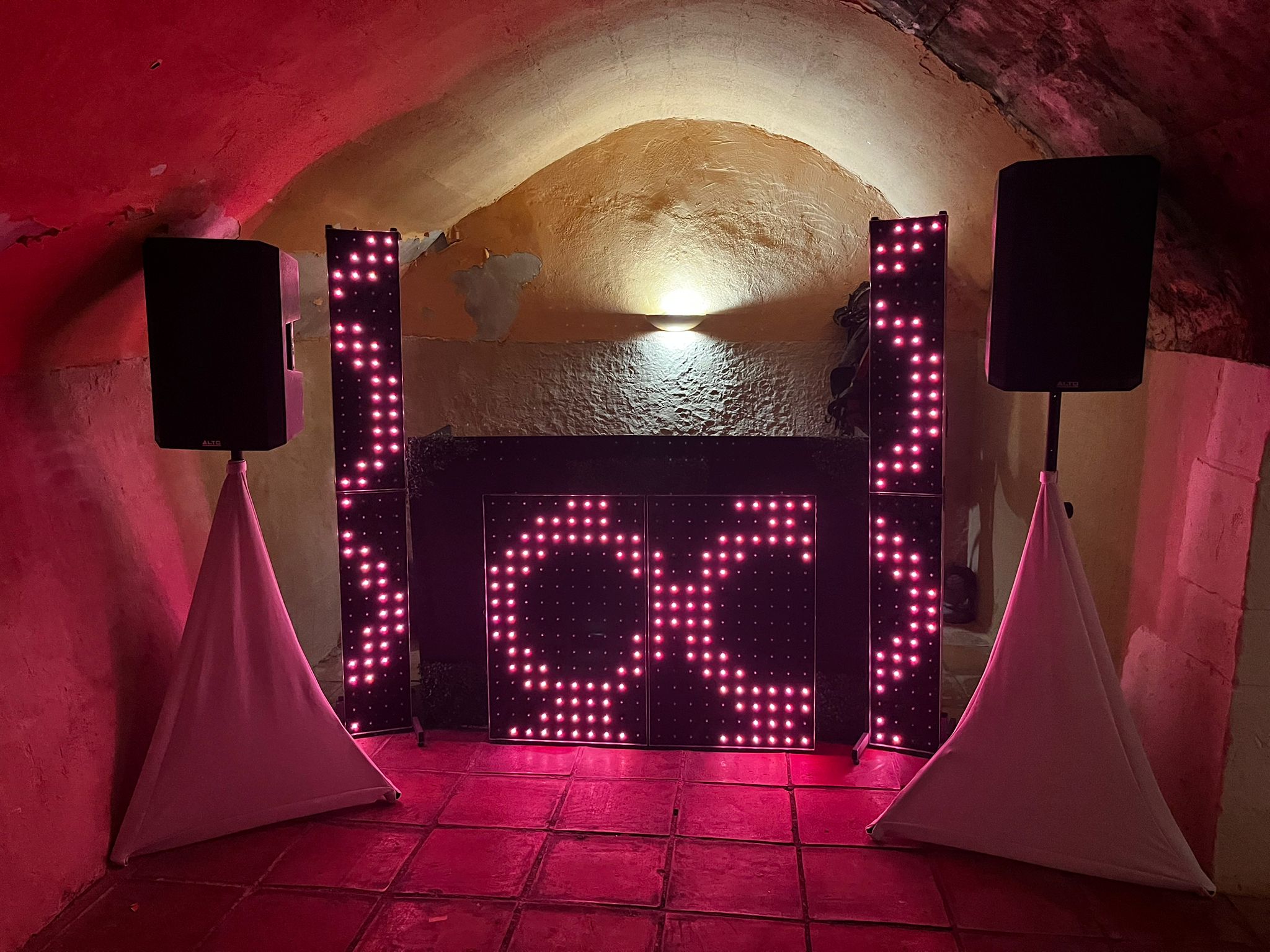 Cabina DJ con frontal LED rosa en bodega abovedada